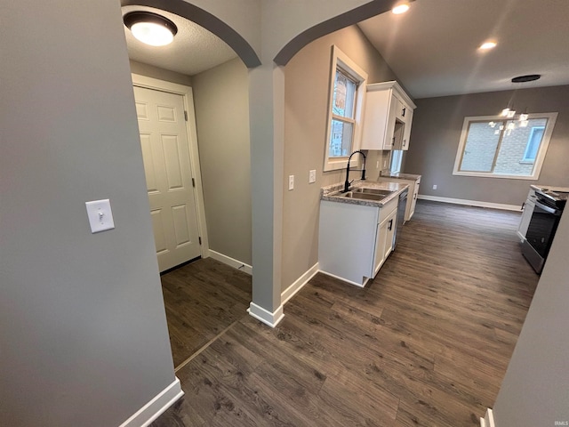 kitchen featuring sink, white cabinets, dark wood-type flooring, and stainless steel range with electric stovetop