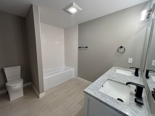 bathroom featuring vanity, a bath, toilet, and a textured ceiling