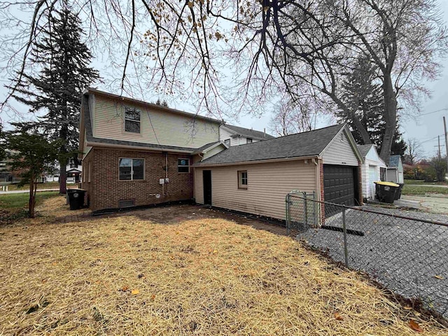 back of house with a yard, a garage, and an outdoor structure