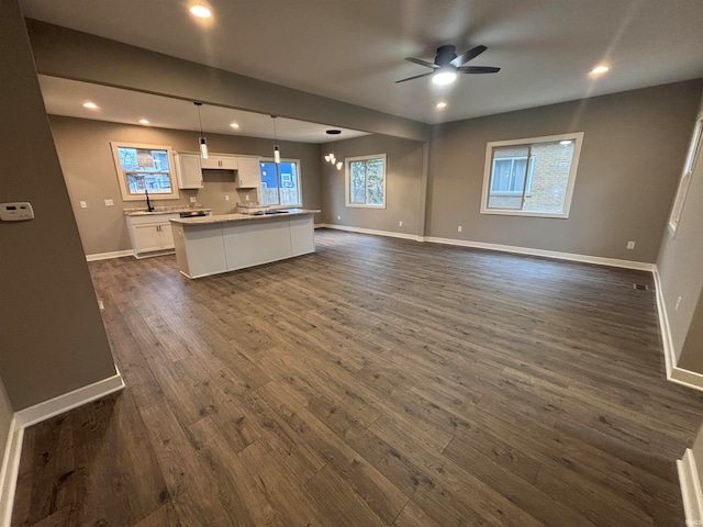 unfurnished living room with ceiling fan with notable chandelier, dark hardwood / wood-style floors, and sink