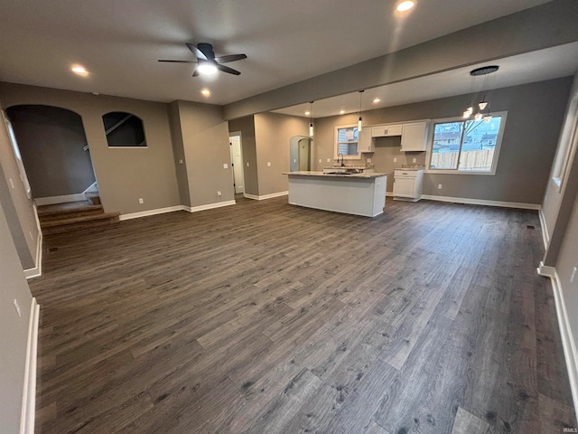 unfurnished living room featuring ceiling fan with notable chandelier, dark hardwood / wood-style flooring, and sink