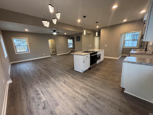 kitchen featuring white cabinetry, a center island, dark wood-type flooring, hanging light fixtures, and stainless steel range with electric stovetop