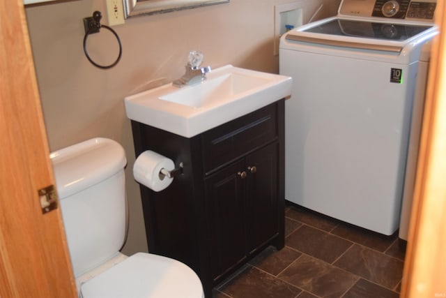 bathroom featuring toilet, vanity, and washer / dryer