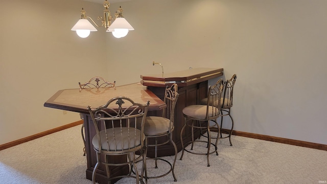 dining space featuring a chandelier, bar area, and light colored carpet