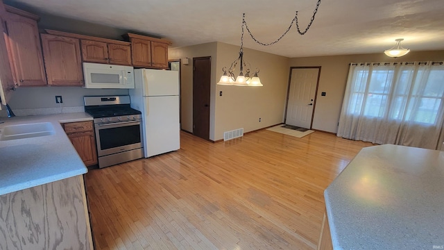 kitchen with sink, an inviting chandelier, decorative light fixtures, white appliances, and light wood-type flooring