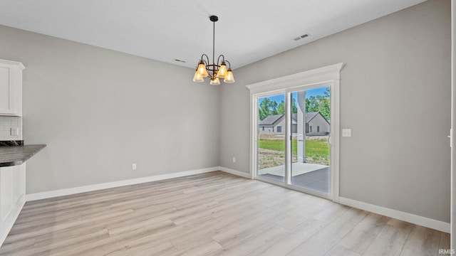 unfurnished dining area with light hardwood / wood-style flooring and a chandelier