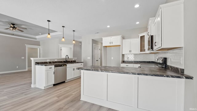 kitchen with white cabinets, decorative light fixtures, stainless steel appliances, and light hardwood / wood-style flooring