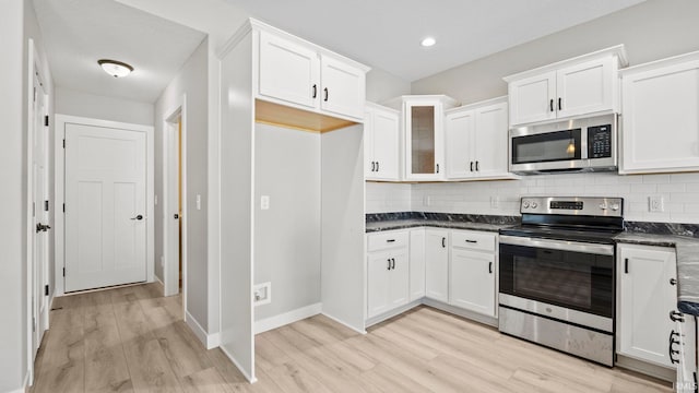 kitchen featuring white cabinets, light wood-type flooring, stainless steel appliances, and tasteful backsplash