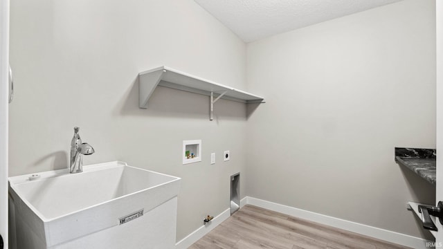 clothes washing area with washer hookup, light wood-type flooring, a textured ceiling, electric dryer hookup, and sink