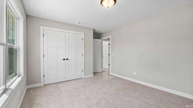 unfurnished bedroom featuring light carpet and a closet