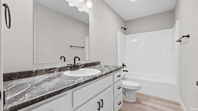 full bathroom with vanity, toilet, wood-type flooring, and washtub / shower combination