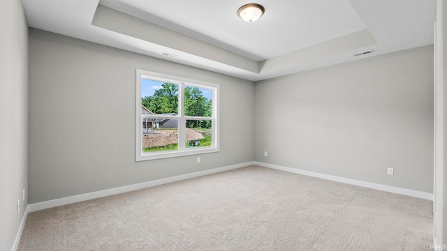 carpeted empty room with a tray ceiling