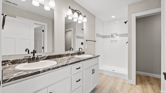 bathroom with hardwood / wood-style floors, vanity, and a tile shower