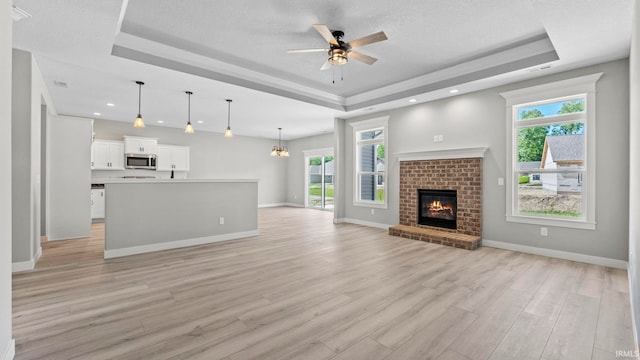 unfurnished living room featuring a tray ceiling and light hardwood / wood-style flooring