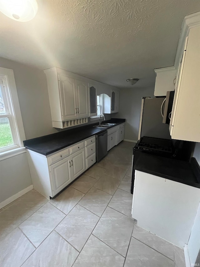 kitchen featuring white cabinets, refrigerator, sink, stainless steel dishwasher, and a textured ceiling