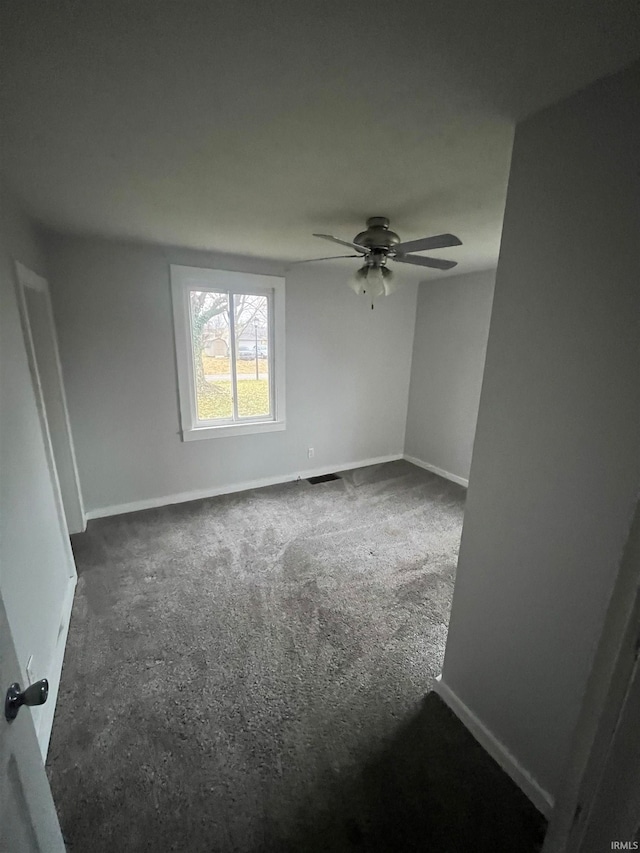 spare room with ceiling fan and dark colored carpet