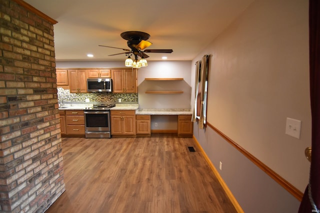 kitchen featuring hardwood / wood-style floors, ceiling fan, built in desk, tasteful backsplash, and stainless steel appliances