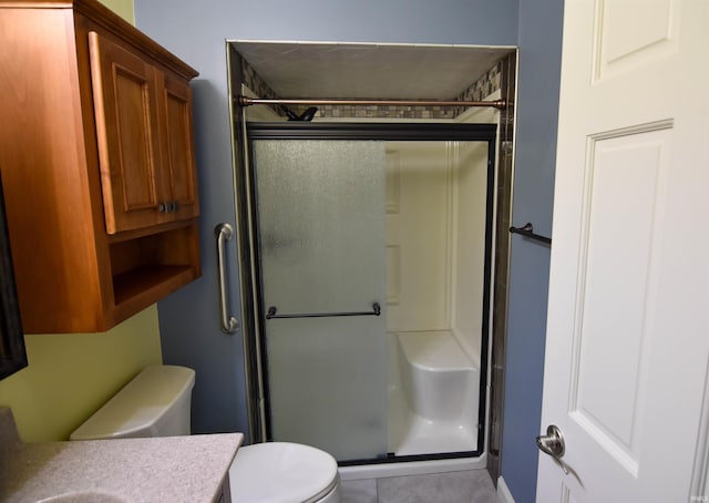 bathroom with tile patterned flooring, vanity, toilet, and a shower with shower door