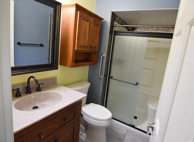 bathroom featuring toilet, a shower with door, vanity, and tile patterned flooring