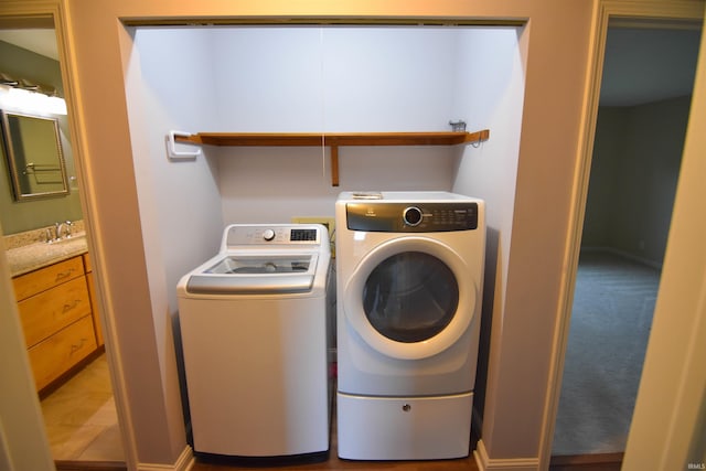 laundry area featuring tile patterned floors, separate washer and dryer, and sink