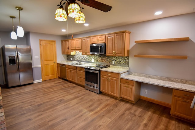 kitchen with decorative backsplash, appliances with stainless steel finishes, sink, pendant lighting, and light hardwood / wood-style flooring