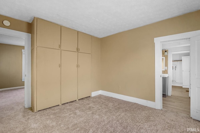 unfurnished bedroom featuring a closet, light colored carpet, and a textured ceiling