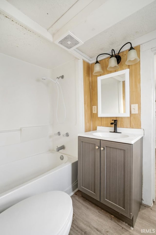 full bathroom with shower / washtub combination, vanity, a textured ceiling, and hardwood / wood-style flooring