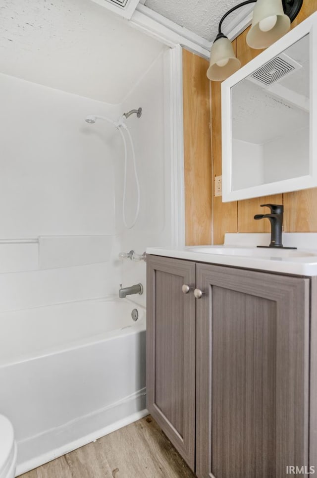 full bathroom featuring vanity, a textured ceiling, bathing tub / shower combination, hardwood / wood-style floors, and toilet