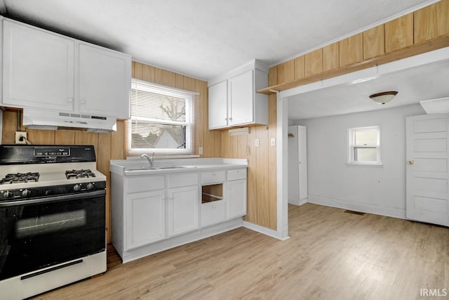 kitchen with white cabinets, white gas stove, plenty of natural light, and range hood