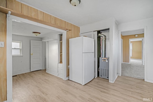 unfurnished bedroom with light wood-type flooring, white fridge, and a closet