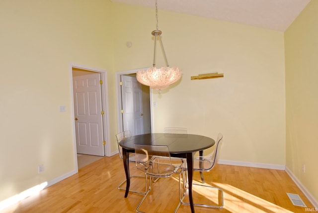 dining area featuring hardwood / wood-style floors, high vaulted ceiling, and a notable chandelier