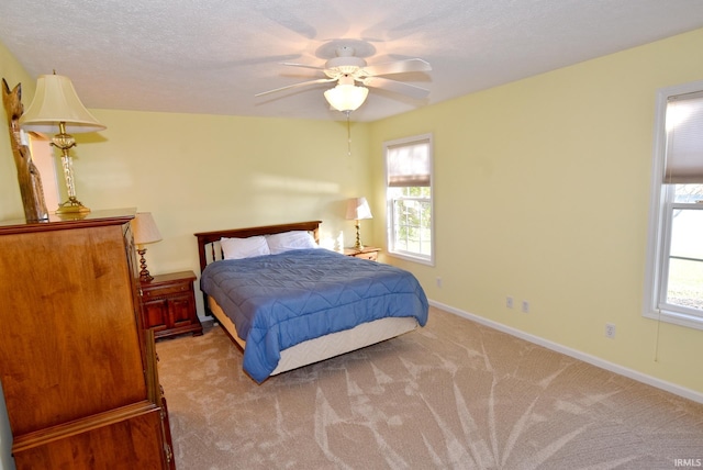 carpeted bedroom with ceiling fan and a textured ceiling