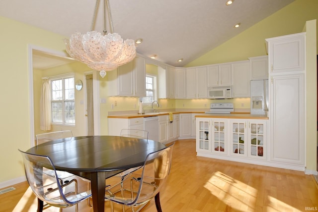 kitchen featuring light wood-type flooring, pendant lighting, white appliances, and white cabinetry