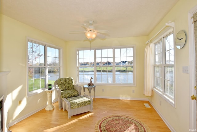 sunroom featuring a water view, ceiling fan, and a healthy amount of sunlight