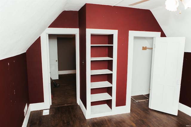 interior space featuring built in shelves, dark hardwood / wood-style floors, lofted ceiling, and ceiling fan