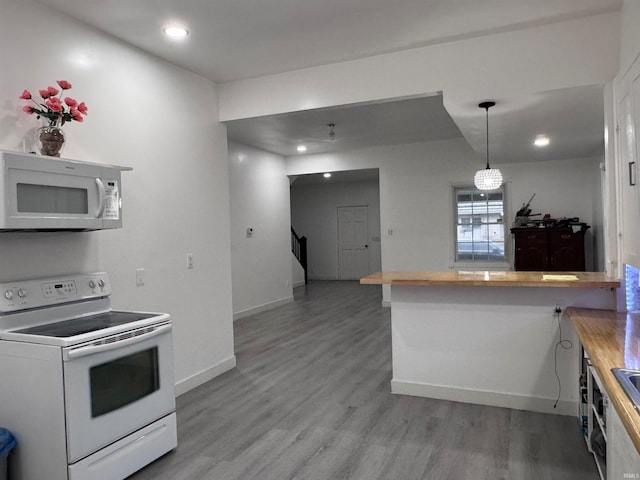 kitchen featuring hardwood / wood-style flooring, decorative light fixtures, white appliances, and kitchen peninsula