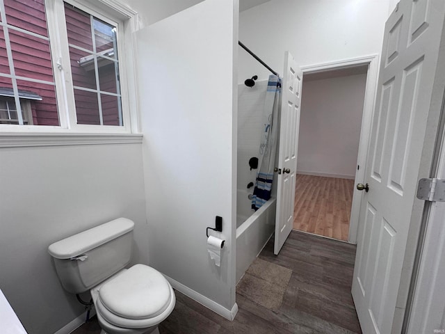 bathroom with wood-type flooring, tiled shower / bath combo, and toilet