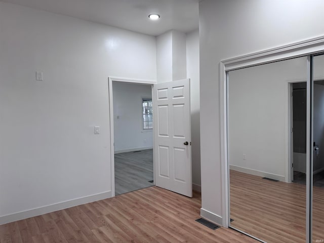 unfurnished bedroom with light wood-type flooring and a closet