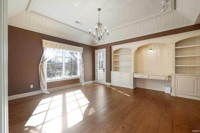 spare room featuring built in features, a chandelier, wood-type flooring, vaulted ceiling, and ornamental molding