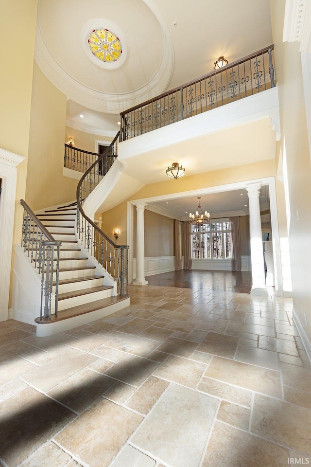 interior space with ornate columns, a chandelier, a high ceiling, and ornamental molding