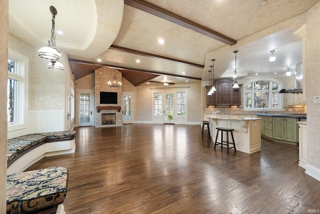 living room with lofted ceiling with beams, a stone fireplace, dark hardwood / wood-style flooring, and sink