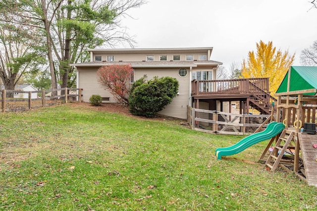 back of property with a playground, a wooden deck, and a yard