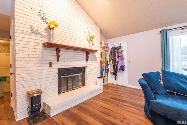 living room with a brick fireplace, wood-type flooring, and lofted ceiling