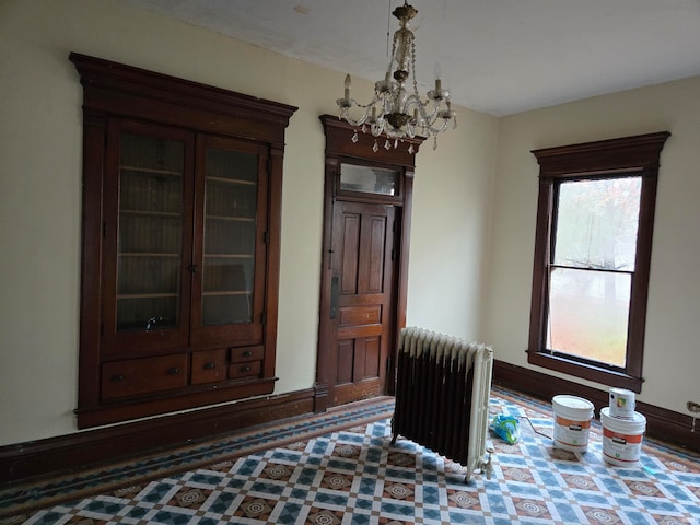 unfurnished room featuring radiator heating unit and a chandelier