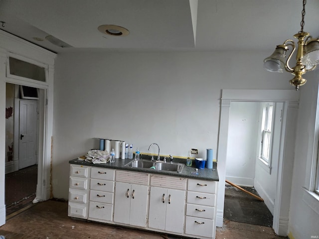 kitchen with white cabinets, vaulted ceiling, sink, and an inviting chandelier