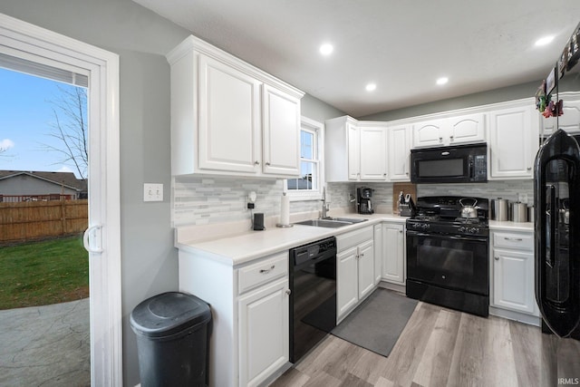 kitchen with white cabinetry, sink, black appliances, and light hardwood / wood-style floors