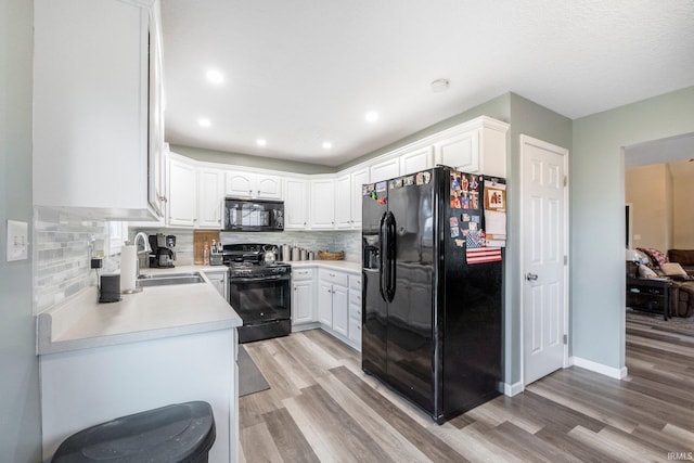 kitchen with white cabinets, sink, light hardwood / wood-style flooring, and black appliances