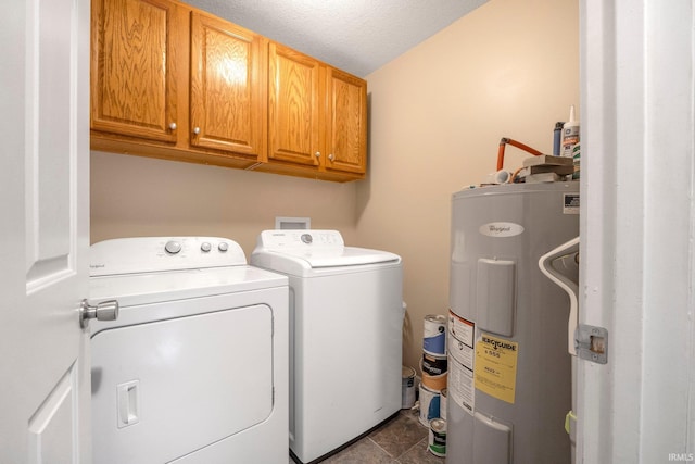 laundry area featuring cabinets, a textured ceiling, electric water heater, separate washer and dryer, and dark tile patterned flooring