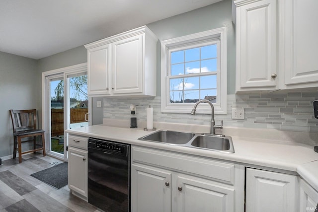 kitchen featuring plenty of natural light, sink, white cabinetry, and black dishwasher