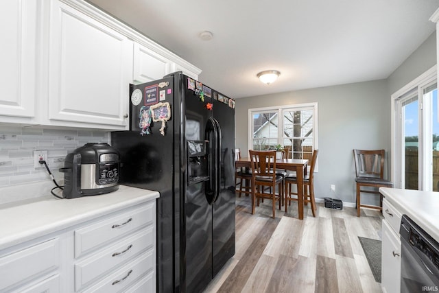 kitchen with black refrigerator with ice dispenser, plenty of natural light, white cabinets, and stainless steel dishwasher